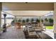 Covered patio area with cushioned outdoor seating, dining table, and BBQ at 21387 W Meadowbrook Ave, Buckeye, AZ 85396