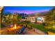 Backyard area with a stone fire pit, built-in grill, well-manicured lawn, and elegant lighting for outdoor gatherings at 2174 E Avenida Del Valle Ct, Gilbert, AZ 85298