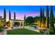 Inviting backyard with a sparkling pool, covered patio, lush greenery, and elegant lighting for evening enjoyment at 2174 E Avenida Del Valle Ct, Gilbert, AZ 85298