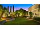 Evening shot of backyard with elegant lighting, lush landscaping, and a cozy seating area creating an inviting outdoor space at 2174 E Avenida Del Valle Ct, Gilbert, AZ 85298