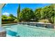 Swimming pool with stone water features, bordered by lush landscaping and mature trees in a private backyard at 2174 E Avenida Del Valle Ct, Gilbert, AZ 85298