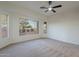 Spacious bedroom with neutral carpet, ceiling fan, and large windows that provide backyard views at 21913 N Pedregosa Ct, Sun City West, AZ 85375