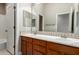 Bathroom with double sinks, wood cabinets, a large mirror, and doorway with view of bathtub at 26015 N 85Th Dr, Peoria, AZ 85383