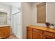 Bright bathroom featuring a walk-in shower with glass doors, wood cabinets, and a window with woven shades at 28351 N 130Th Dr, Peoria, AZ 85383