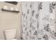 This bathroom features a toilet with a decorative shower curtain and overhead shelving at 38085 W San Capistrano Ave, Maricopa, AZ 85138