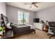 This bedroom offers a large window, ceiling fan, carpet floor and is accented by a dark wood bed frame at 38085 W San Capistrano Ave, Maricopa, AZ 85138