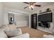 Bright living room with carpet flooring and a ceiling fan, alongside built-in dark wood shelving at 38085 W San Capistrano Ave, Maricopa, AZ 85138