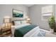 Cozy bedroom featuring a plush bed with decorative pillows and a green throw, next to a window and plant at 4265 E John St, Gilbert, AZ 85295
