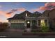 Charming single-Gathering home featuring a two-car garage, stylish wood accents, and beautiful landscaping at dusk at 4265 E John St, Gilbert, AZ 85295