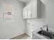 Well-lit laundry room with a sink, overhead cabinets, and connections for a washer and dryer at 4265 E John St, Gilbert, AZ 85295