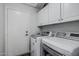 Functional laundry room featuring white cabinets and modern, front-loading washer and dryer units at 4665 E Goldfinch Gate Ln, Phoenix, AZ 85044