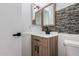 Modern bathroom featuring a wood vanity with black hardware, decorative tile, and dual mirrors at 907 W Laguna Dr, Tempe, AZ 85282