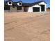 A white house with black trim and a black roof, showing a large garage and a spacious yard at 11142 E Copper Dust Trl, Florence, AZ 85132