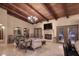Living room with wooden beam ceiling, travertine tile flooring, and fireplace. French doors to the backyard pool at 10365 E Paradise Dr, Scottsdale, AZ 85260
