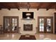 Cozy living room with wood-beamed ceilings, tile floors, a stone fireplace and doors to the pool area at 10365 E Paradise Dr, Scottsdale, AZ 85260