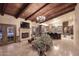 Expansive living room with wooden beam ceiling, travertine tile flooring, fireplace and open to the kitchen at 10365 E Paradise Dr, Scottsdale, AZ 85260