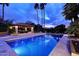 Twilight view of the sparkling pool with a covered patio and towering palm trees in the background at 10365 E Paradise Dr, Scottsdale, AZ 85260