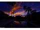 Twilight view of the stunning pool with palm trees and a colorful sunset reflecting on the water at 10365 E Paradise Dr, Scottsdale, AZ 85260