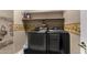 Laundry room features a dark washer and dryer beneath a shelf with laundry products at 11713 W Tonto St, Avondale, AZ 85323