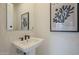 Stylish powder room featuring a modern pedestal sink, unique tile accent wall, and elegant wall art at 12328 E Black Rock Rd, Scottsdale, AZ 85255