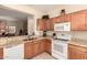 Functional kitchen with warm wood cabinetry, granite countertops, and white appliances at 15074 W Cactus Ridge Way, Surprise, AZ 85374