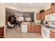 Open kitchen showcases wood cabinets, light countertops, white appliances, and seamless flow to the living room at 15074 W Cactus Ridge Way, Surprise, AZ 85374