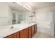 Bathroom with dual sinks, framed mirrors, bath tub, and a glass-enclosed shower at 15123 W Custer Ln, Surprise, AZ 85379