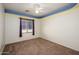 Bedroom with neutral carpet, ceiling fan, and window with wood trim at 15123 W Custer Ln, Surprise, AZ 85379