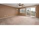 Spacious carpeted bedroom with neutral paint, ceiling fan, window, and patio door at 15123 W Custer Ln, Surprise, AZ 85379