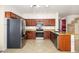 Spacious kitchen featuring wood cabinets, stainless steel appliances, granite countertops, and tile flooring at 15123 W Custer Ln, Surprise, AZ 85379