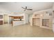 Open-concept living room with tile flooring, ceiling fan, kitchen view and custom shelving at 15123 W Custer Ln, Surprise, AZ 85379