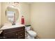Powder room featuring a dark wood vanity with granite countertop, round mirror, and a beige painted wall at 15123 W Custer Ln, Surprise, AZ 85379