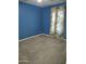 Cozy bedroom with blue walls, carpeted floors, and a bright window with decorative curtains at 1875 N St Francis Pl, Casa Grande, AZ 85122