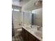Bright bathroom featuring double sinks with dark wood vanity, shower-tub combo, and neutral tile at 19427 N Toya St, Maricopa, AZ 85138