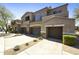 Exterior of a multi-level townhome featuring desert landscaping, and multiple car garages with stone accents at 19475 N Grayhawk Dr # 2132, Scottsdale, AZ 85255
