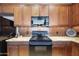 Close up of kitchen with sleek black appliances and warm, wood cabinets at 19475 N Grayhawk Dr # 2132, Scottsdale, AZ 85255