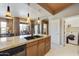 Granite island kitchen featuring modern lighting, wood cabinetry, and open access to living and laundry rooms at 19475 N Grayhawk Dr # 2132, Scottsdale, AZ 85255