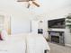 Bright primary bedroom features a decorative fireplace with tv above, ceiling fan, and carpet at 235 S San Gregorio Ln, Casa Grande, AZ 85194
