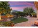 Backyard retreat showcasing a firepit, artificial turf, lush landscaping, and paver patio at 27280 N Makena Pl, Peoria, AZ 85383