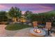 Backyard with a fire pit, artificial turf, lush landscaping, trees, and a paver patio at 27280 N Makena Pl, Peoria, AZ 85383
