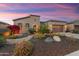 Beautiful home with a lush landscaped yard featuring cacti, colorful flowers, and a stone-accented garage at 27280 N Makena Pl, Peoria, AZ 85383