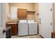 Bright laundry room with front loading washer/dryer, tile floors, and wooden cabinets at 27280 N Makena Pl, Peoria, AZ 85383