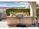 Outdoor kitchen featuring a built-in grill, counter space, and lush green landscaping at 27280 N Makena Pl, Peoria, AZ 85383