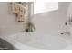 Close-up of a white bathtub with silver faucet and a small window with a plant next to it at 3023 E Silversmith Trl, San Tan Valley, AZ 85143