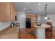 Spacious kitchen featuring wood cabinetry, tile floors, black appliances, and a functional island at 3023 E Silversmith Trl, San Tan Valley, AZ 85143