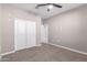 A neutral carpeted bedroom with a ceiling fan and closet with sliding doors at 30323 W Sheila Ln, Buckeye, AZ 85396