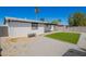 This backyard features low maintenance gravel, grass, palm tree, and a white colored house at 3437 E Acoma Dr, Phoenix, AZ 85032