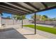The covered patio boasts concrete tiles, dark painted ceiling and a view of the grassy lawn at 3437 E Acoma Dr, Phoenix, AZ 85032