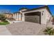 Home exterior showcasing a brick driveway, front yard, and warm beige stucco, creating an inviting curb appeal at 36053 N Stoneware Dr, Queen Creek, AZ 85140