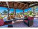 Inviting outdoor living area with a cushioned sofa, armchairs, and a coffee table, framed by lush landscaping and a red tiled patio at 36053 N Stoneware Dr, Queen Creek, AZ 85140